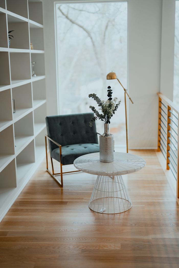 about-us Elegant interior featuring an armchair and centerpiece table with a plant, framed by a large window.